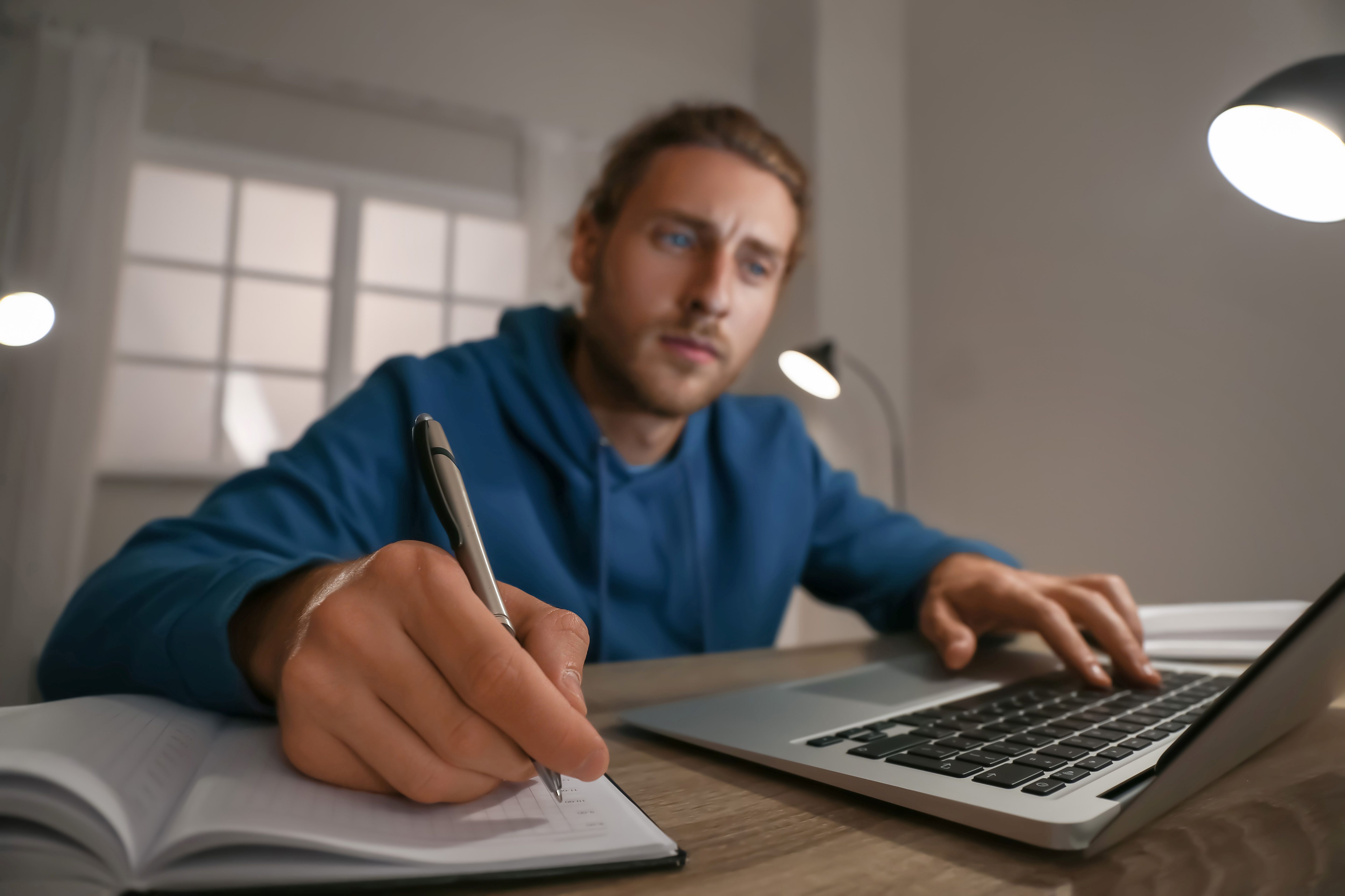 man taking notes on laptop