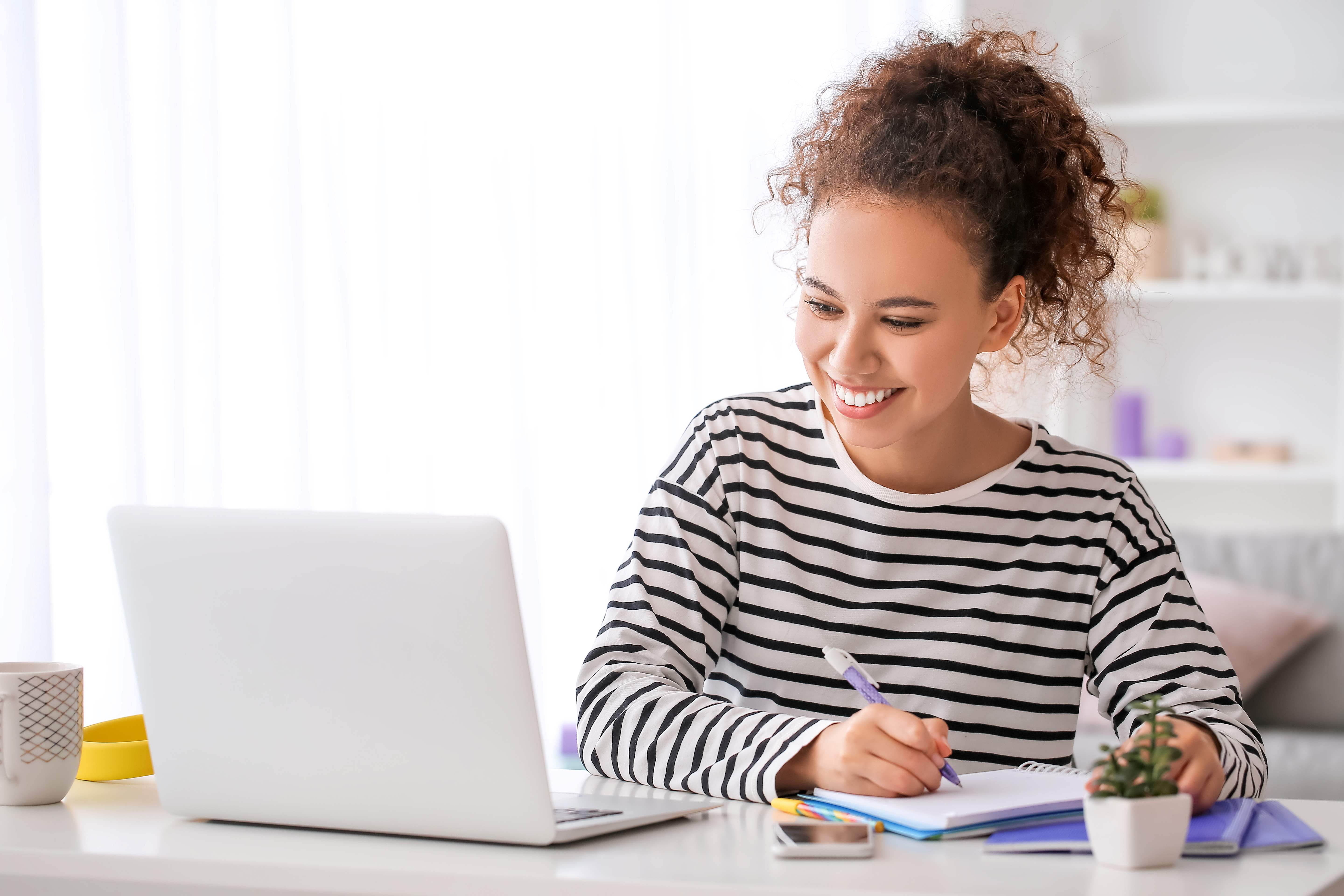 woman taking notes on laptop and smiling